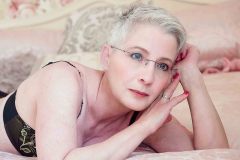 mature woman laying on bed for  a glamourous photos