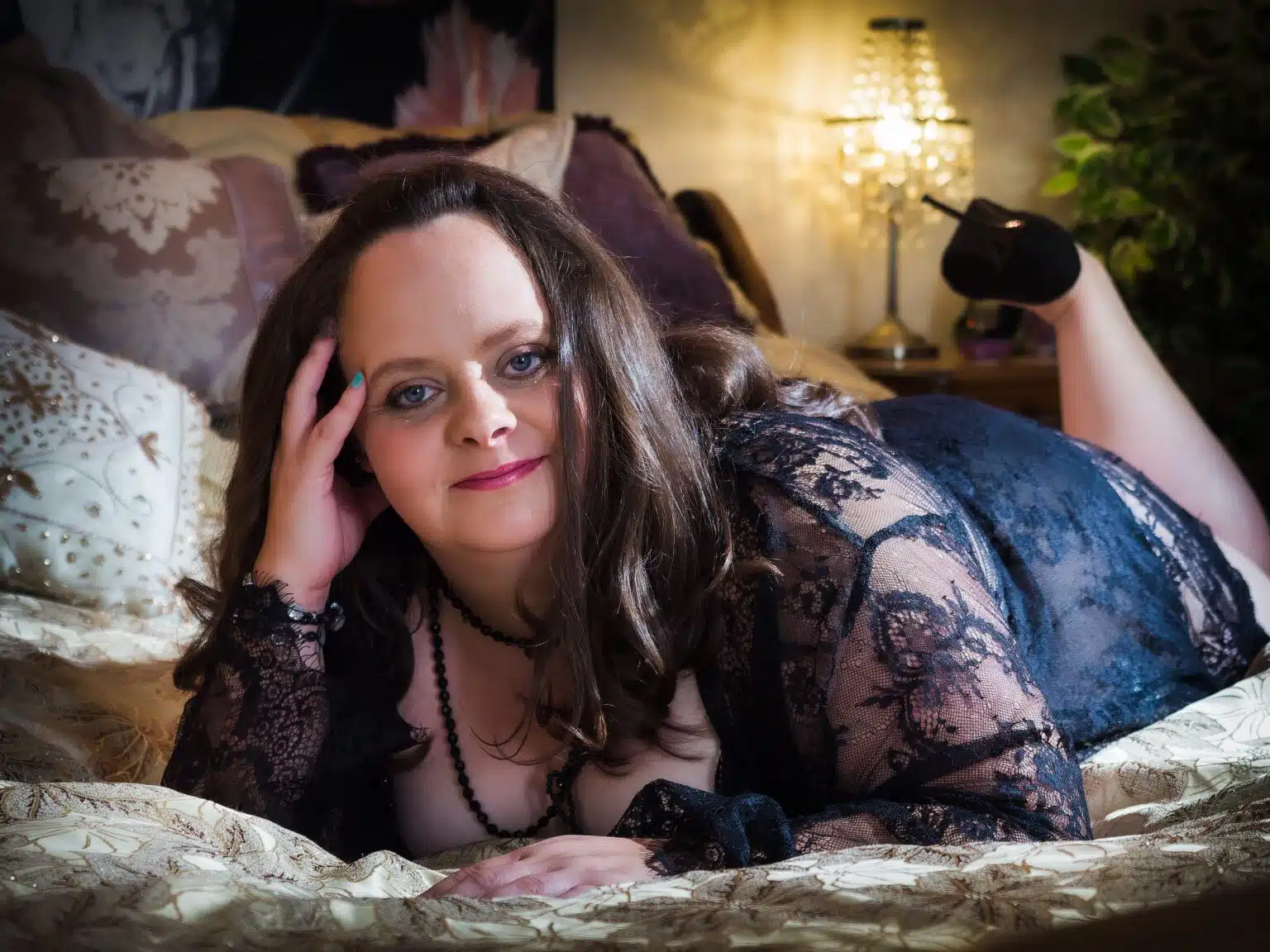 Symply Boudoir woman in lace outfit relaxing on a bed
