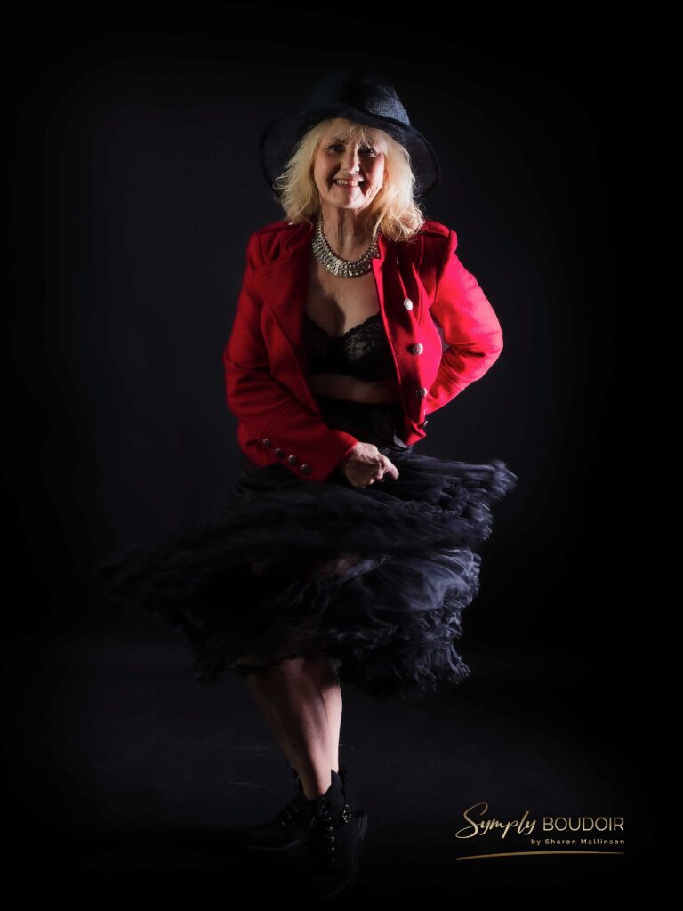 older woman in red jacket and hat boudoir shoot