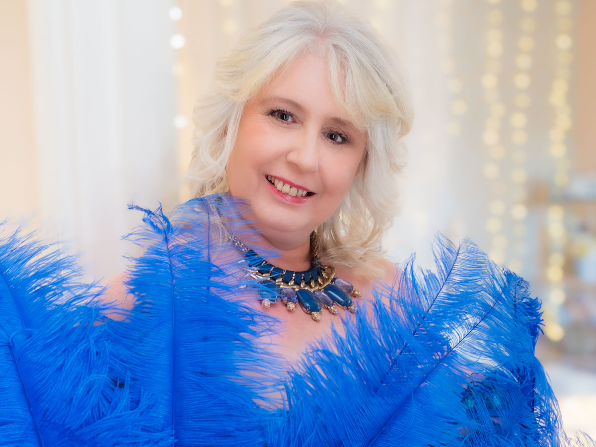 mature lady with blue feathers for 50 over 50 project