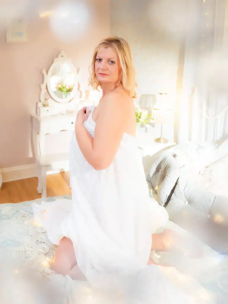 woman wrapped in white sheet in boudoir