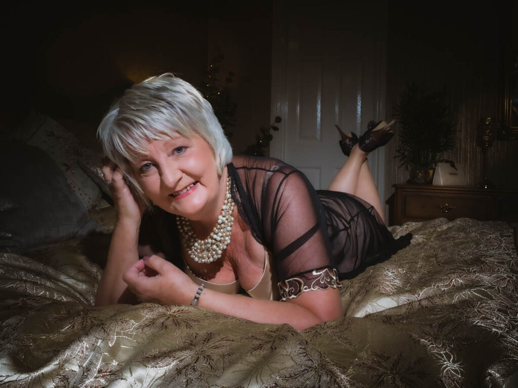 mature woman lying on a bed in black for her boudoir shoot