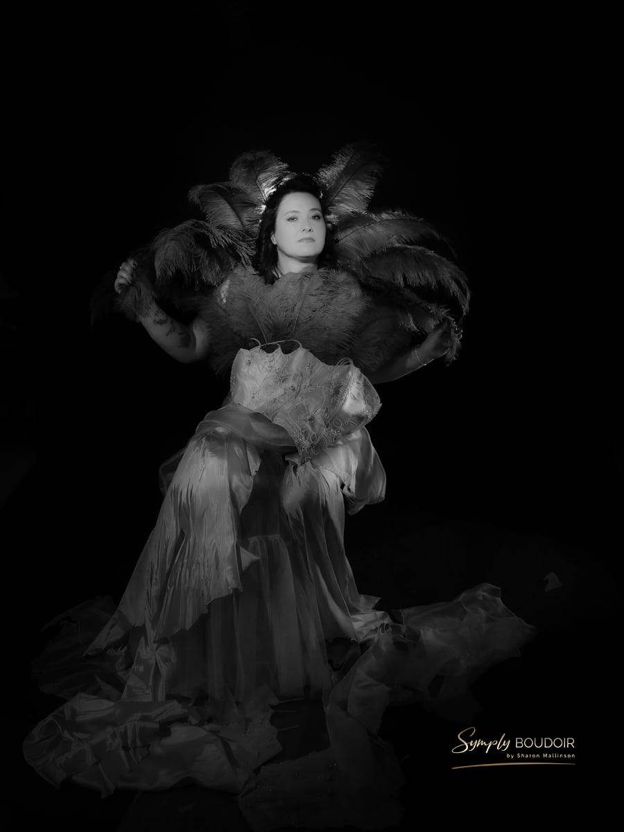 woman in ripped wedding dress with feathers behind